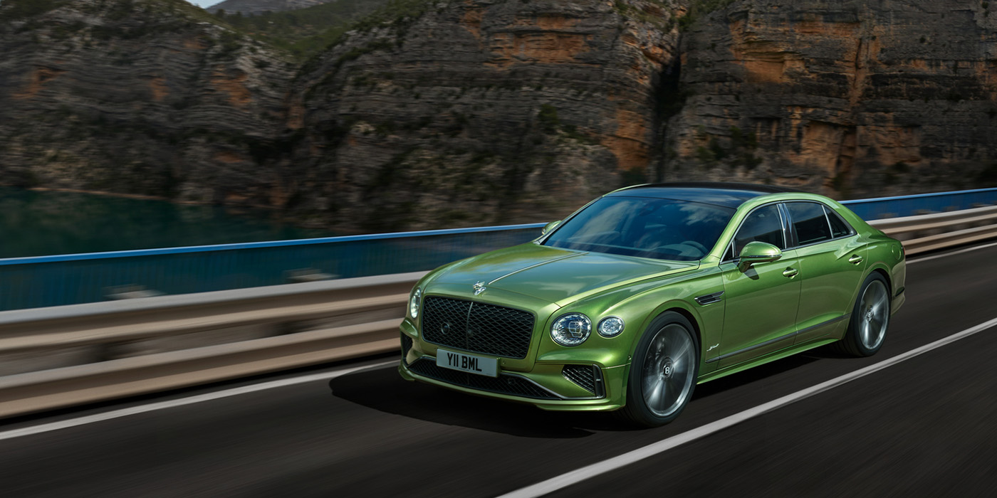 Bentley Bordeaux Bentley New Flying Spur Speed v8 hybrid sedan driving dynamically on a mountain road in Tourmaline Green paint
