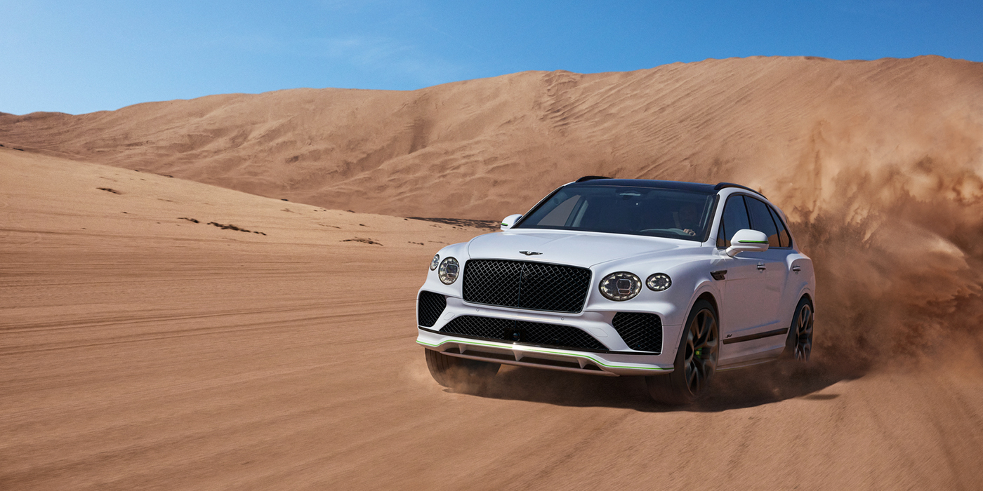 Bentley Bordeaux Bentley Bentayga Speed SUV front three quarter in Snow Quarts Pearlescent by Mulliner white paint driving dynamically through the desert