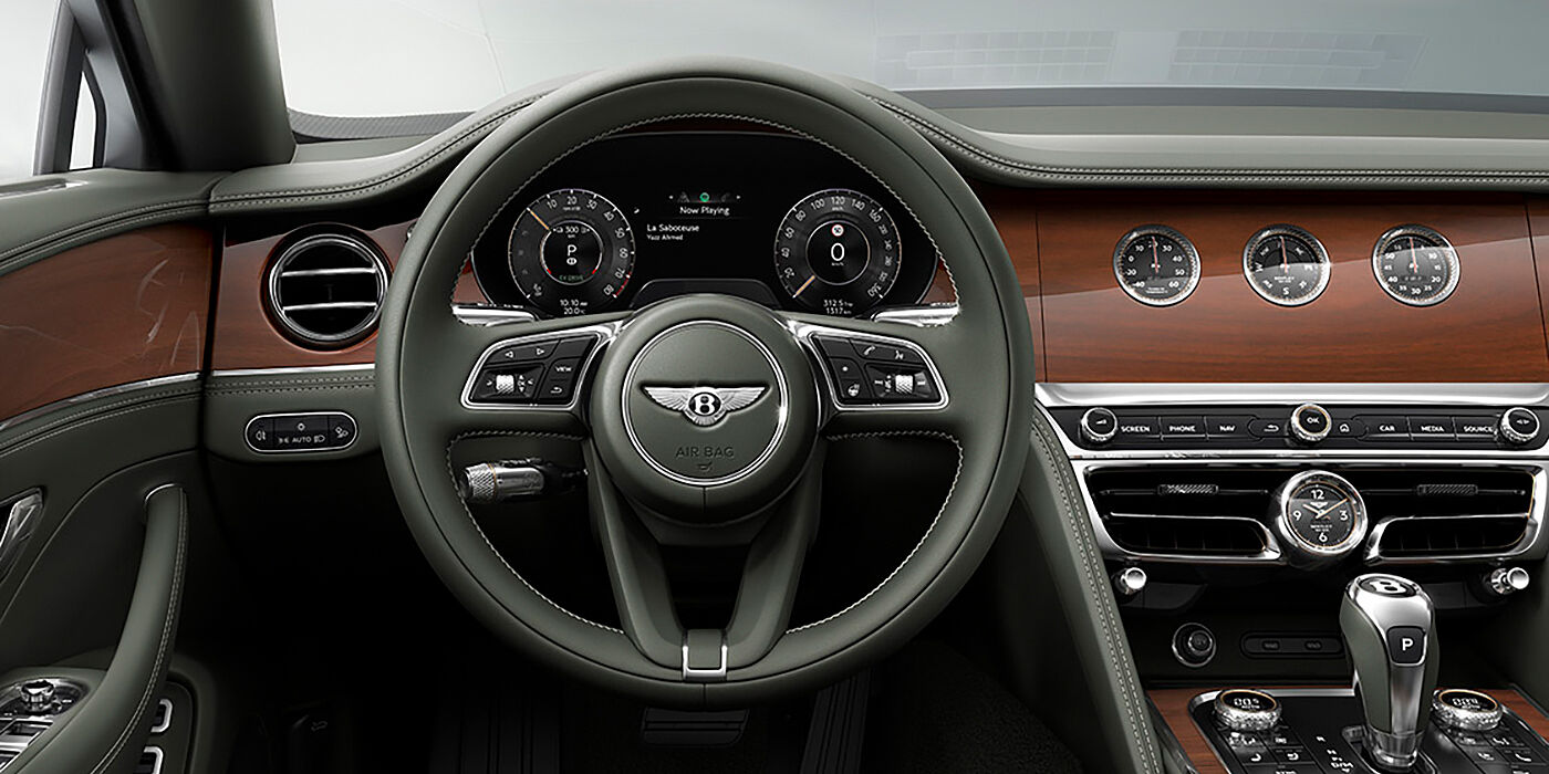 Bentley Bordeaux New Bentley Flying Spur sedan front cabin in Cumbrian Green hide and Crown Cut walnut veneer showing steering wheel and Rotating Display with three clocks on face