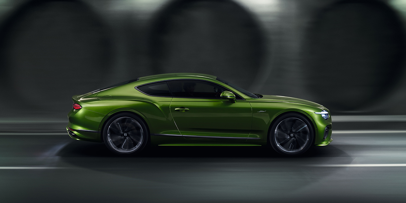 Bentley Bordeaux Bentley Continental GT coupe in Tourmaline Green paint driving in profile on a dark road